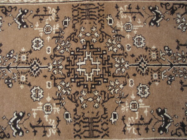Tan rug with a dense traditional geometric and floral pattern in dark brown and cream.