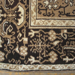 Ornate floral rug border in dark brown, tan, and cream lies partially on a wood plank floor.