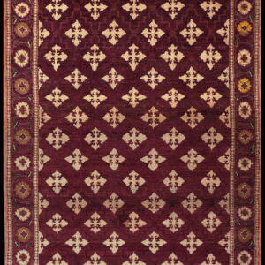 Deep red rug with light beige geometric trellis patterns surrounded by a multi-colored floral border.