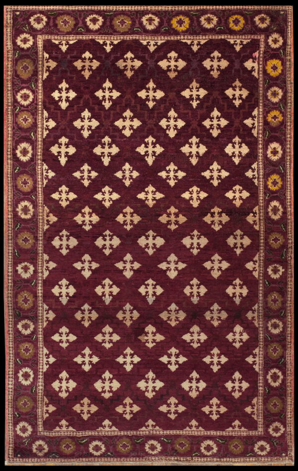 Deep red rug with light beige geometric trellis patterns surrounded by a multi-colored floral border.