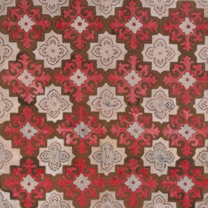 Textured rug with large repeating geometric medallions in red, brown, and beige on wood.