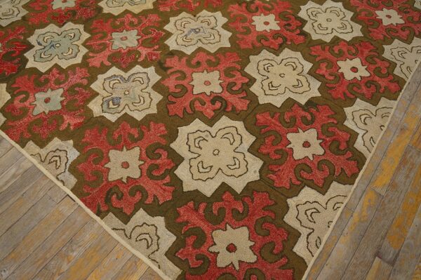 Diagonal view of a textured rug with red, beige, and olive floral medallions on distressed wood floor.