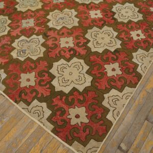 Repeating red, brown, and cream geometric pattern rug resting on distressed hardwood plank flooring.