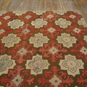 Repeating red, cream, and dark brown geometric pattern rug sits on rustic wooden flooring.