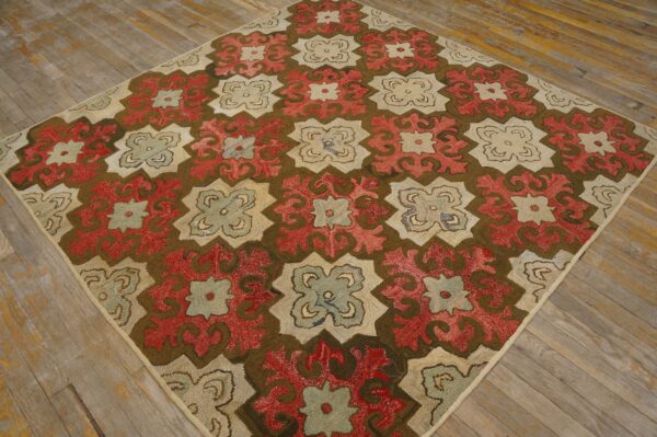 Repeating red, cream, and sage floral-geometric motifs fill this high-texture rug on rustic wooden flooring.
