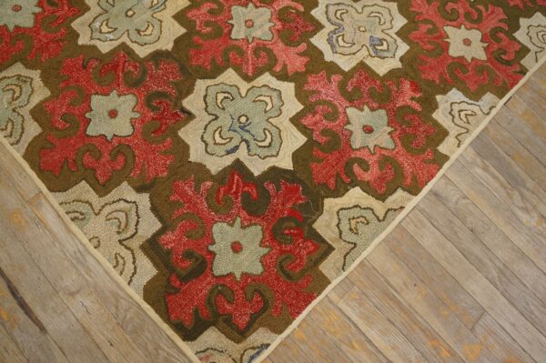 Low-pile textured rug in red, olive green, cream, and pale blue, shown on distressed wood flooring.