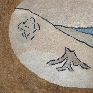 Textured rug detail with a light oval featuring abstract blue and gray nature motifs on a dark tan ground.