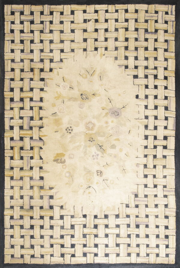 Cream rug with a woven lattice border in beige and dark gray surrounding a faint floral center design.