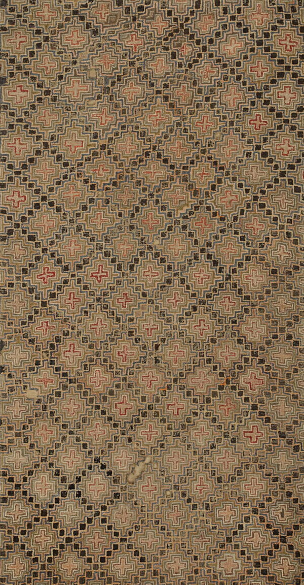 Textured, rectangular rug with stepped geometric patterns in tan, black, muted red, blue, and green.