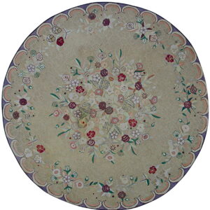 Round sage green rug featuring a multicolored floral pattern and a scalloped border of purple and pink.