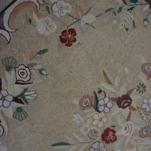 Highly textured, rounded rug featuring a dense floral pattern in muted colors on distressed wood planks.