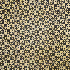 Full view of a low pile rug featuring a dense geometric pattern of black and tan triangles.