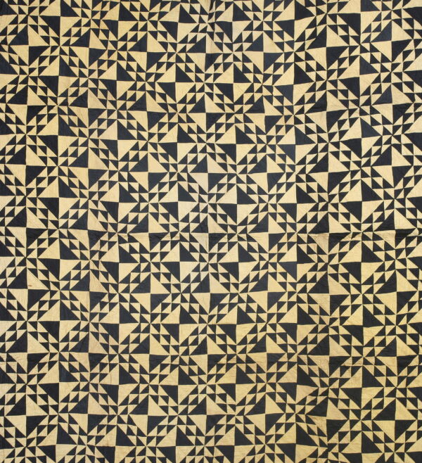 Full view of a low pile rug featuring a dense geometric pattern of black and tan triangles.