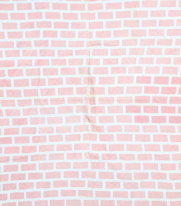 A wrinkled textile featuring a pink and white pattern that mimics a brick wall design.