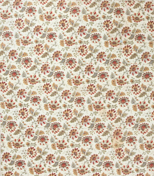Cream rug with an all-over floral design featuring stylized red, rust, and sage leaves and blossoms.