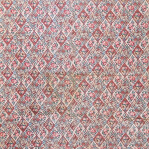 A faded rug with a dense diamond grid featuring alternating red roses and stylized floral baskets.