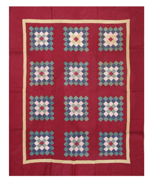 Red square textile featuring twelve multi-color diamond patterns in blue, teal, white, and yellow with a cream border.