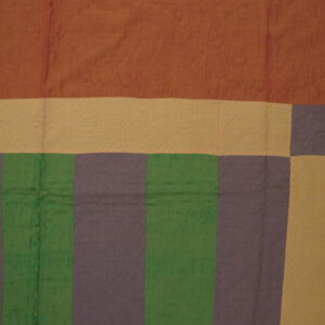 Quilted textile featuring broad stripes of terracotta, tan, green, and mauve laid flat on rustic wood flooring.