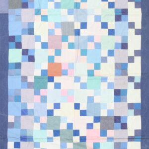 A flatweave rug with a patchwork pattern of blue, pink, lavender, and white squares, framed by a dark blue border.