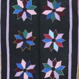 Dark rug with six large colorful star appliqués featuring a lavender border and zigzag stitching details.