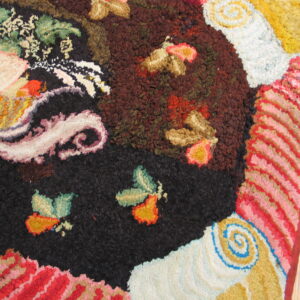 Multicolor textural rug detail featuring abstract florals and swirls in black, red, brown, and gold on wood floor.