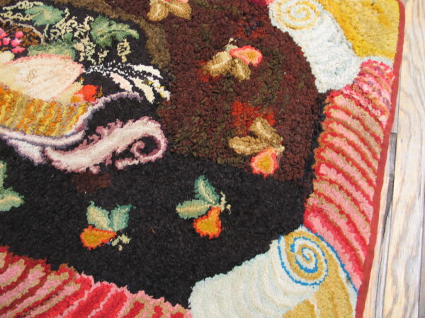 Multicolor textural rug detail featuring abstract florals and swirls in black, red, brown, and gold on wood floor.