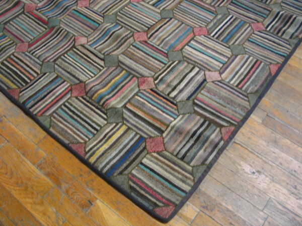 Close-up of a rug corner showing striped hexagonal patches and solid squares resting on light hardwood flooring.