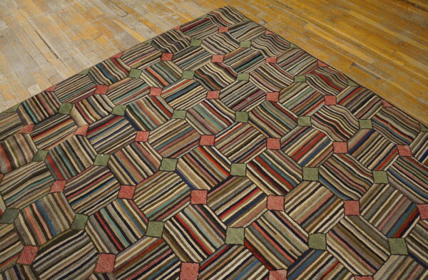 Patchwork rug with multicolored striped octagons and solid green and pink squares rests on distressed wood floor.