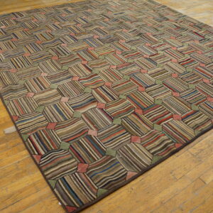 Multicolored rug with a tessellating striped block pattern displayed on distressed hardwood floors.