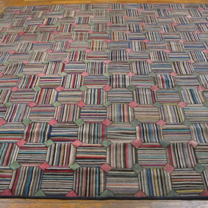 Multicolored striped geometric rug featuring repeating octagons linked by pink and green squares on a wood floor.