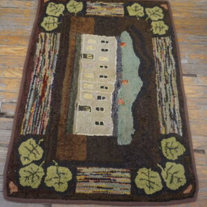Hooked rug with a beige building, teal water, and olive leaf border on distressed wood plank flooring.