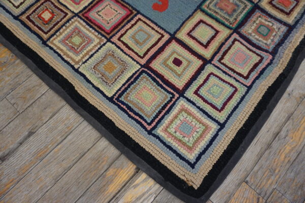 Highly textured rug with multicolored concentric diamonds and a black banded border on distressed wood plank flooring.
