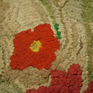 Textured floral rug close-up features red, yellow, and green elements on a chunky beige and tan pile.
