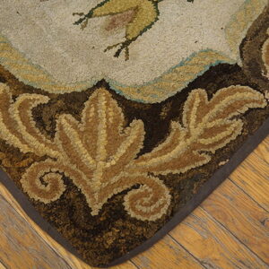 Hooked rug corner featuring brown leaves and light motifs on a textured surface, resting on rustic wooden planks.