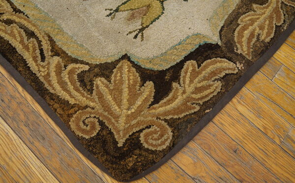 Hooked rug corner featuring brown leaves and light motifs on a textured surface, resting on rustic wooden planks.