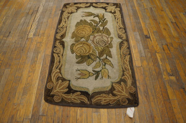 A hooked floral runner in brown, gold, and pale pink rests on rustic wood plank flooring.