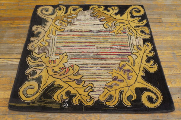 Yellow scrollwork frames a multicolored striped, textured center field on a dark border and plank wood floor.