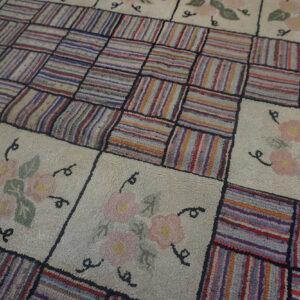 Shaggy rug with alternating blocks of multicolored vertical stripes and cream squares with flowers.
