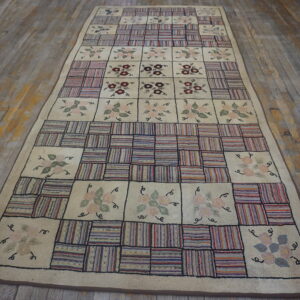 Cream and multicolored runner rug featuring floral motifs alternating with striped patchwork squares on distressed wood floor.