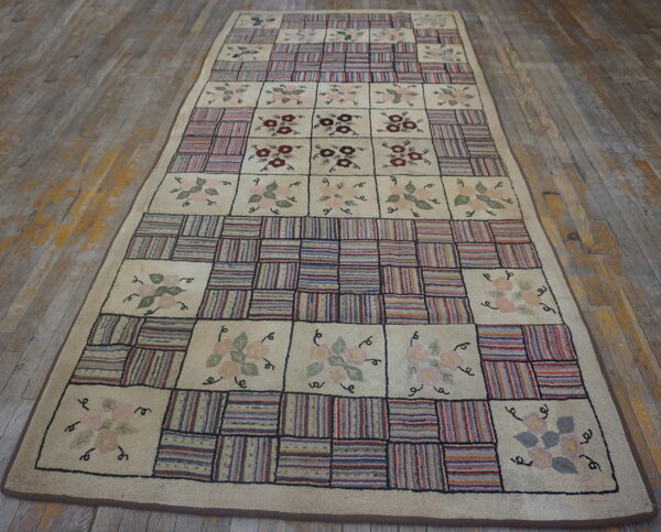 Cream and multicolored runner rug featuring floral motifs alternating with striped patchwork squares on distressed wood floor.