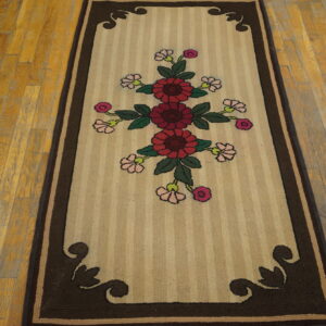 Striped beige runner rug with a central crimson floral pattern and dark brown ornate borders on hardwood.
