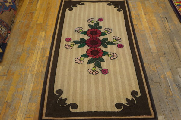 Striped beige runner rug with a central crimson floral pattern and dark brown ornate borders on hardwood.