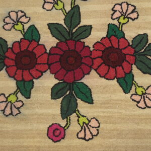 Textured beige rug with a floral pattern of red and pink flowers, dark green leaves, and black outlines.