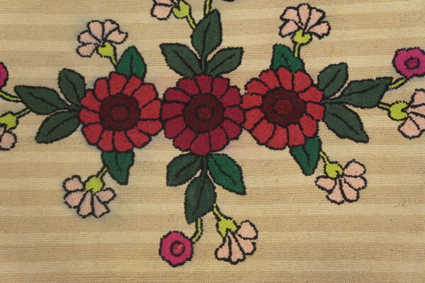 Textured beige rug with a floral pattern of red and pink flowers, dark green leaves, and black outlines.