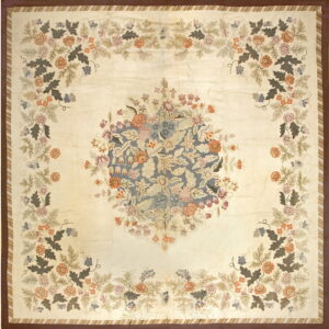 Ivory rug featuring a central blue floral bouquet and four corner sprays; it has striped and solid brown borders.