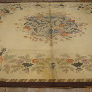 Large cream rug with a blue floral medallion and multicolor vine pattern lies on worn wood floors.
