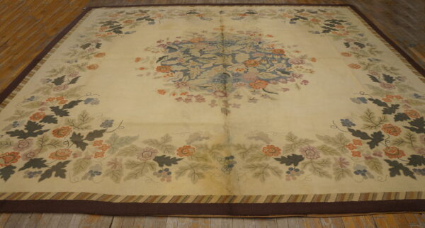 Large cream rug with a blue floral medallion and multicolor vine pattern lies on worn wood floors.