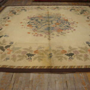 Oversized cream rug with a faded central floral medallion and multi-colored border, resting on wide wood planks.