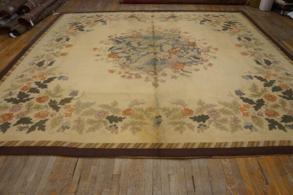 Oversized cream rug with a faded central floral medallion and multi-colored border, resting on wide wood planks.