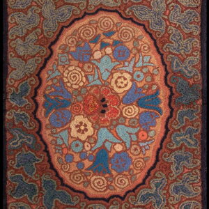 Rustic hooked rug with a central floral medallion pattern in blues, gold, and terracotta.